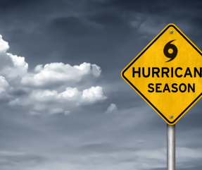 Florida Hurricane Season - a storm shown approaching in the sky, with a warning road sign reading "Hurricane Season" in the front